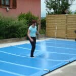 Réalisation et confection textile d'une bâche de sécurité pour piscine. Une personne se trouve sur la bâche pour tester sa résistance