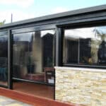 Fermeture de terrasse Ziptrak® transparente offrant une protection solaire, contre la pluie et le vent chez un particulier