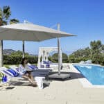 Parasol Caravita avec un pied décentré au bord d'une piscine